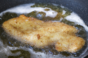 chicken cutlet frying in pan