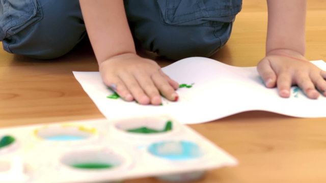 Boy using his hands to make painted handprints