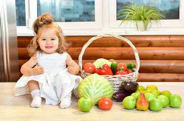 Fototapeta premium Beautiful little girl sitting surrounded by fresh fruits and veg