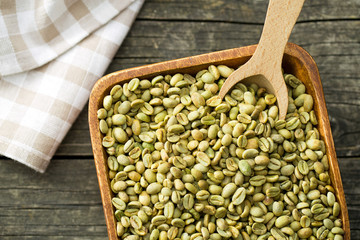 green coffee beans in wooden bowl