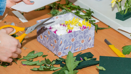 Naklejka na ściany i meble Florist at work with scissors in hand. Woman making the box with