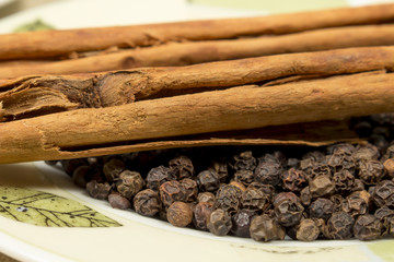 Close-up of black pepper grains and cinnamon sticks