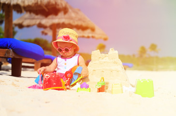 cute little girl building sandcastle on beach