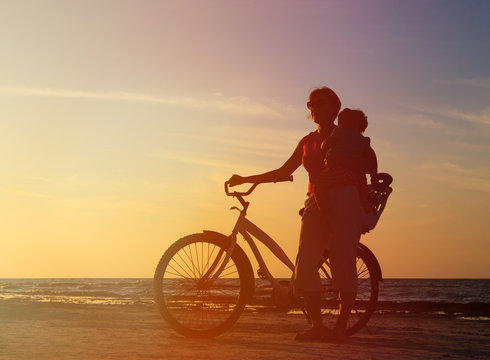 Silhouette of mother and baby biking at sunset