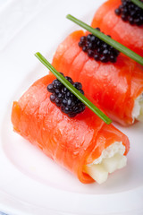 Smoked salmon rolls with cream cheese, black caviar