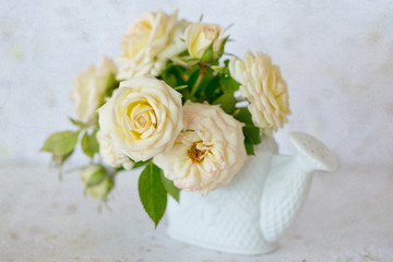 Beautiful fresh cream-colored roses in a vase on a grunge paper background.