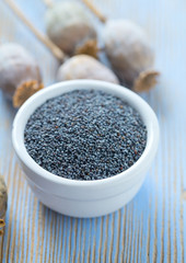 poppy seeds in a bowl on wooden surface
