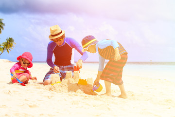 father and two kids playing with sand on beach