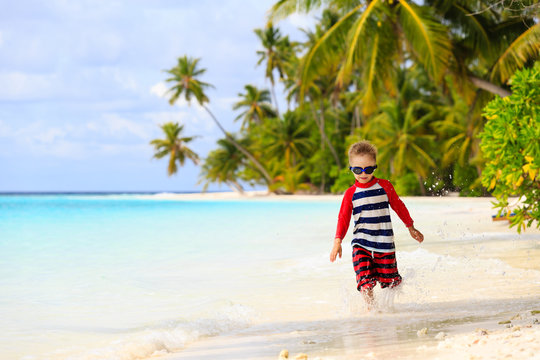 little boy running splashing water on beach