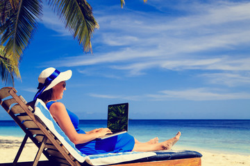 young woman with laptop on tropical beach