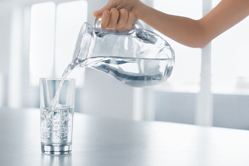 Drink Water. Woman's Hand Pouring Water From Pitcher Into A Glass. Healthy Lifestyle.