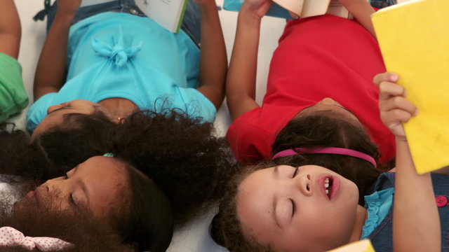 Small group of kids lying down and reading books