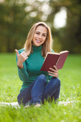 Young woman is reading a book in park