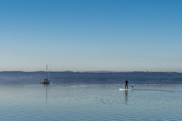 Fototapeta na wymiar Stehpaddler am Starnberger See am herbstlichen Morgen