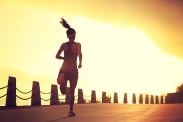 young fitness woman running on sunrise seaside trail