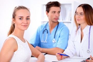 Fototapeta premium Happy blond female patient next to a few doctors in hospital sitting at the table