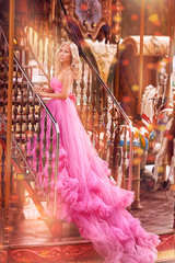 beautiful girl in a chic glamorous pink dress on stairs