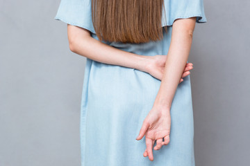Close up of crossed fingers behind woman's back