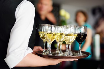 Waitress with dish of champagne and wine glasses