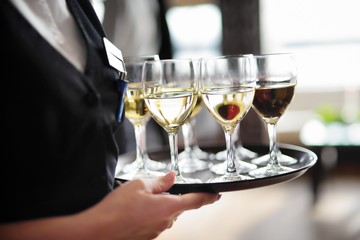Waitress with dish of champagne and wine glasses