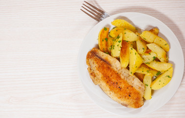 Fried fish fillet and potatoes in a plate