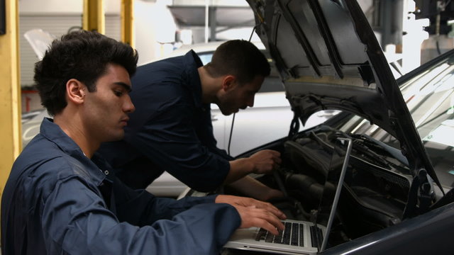 Handsome mechanics overhauling a car