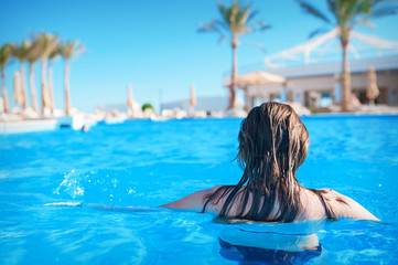 Young woman in the water in a blue swimming pool