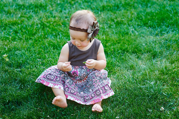 Cute little girl sitting on the grass on a sunny summer day