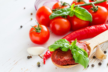 Tomato sauce and ingredients on white wood background