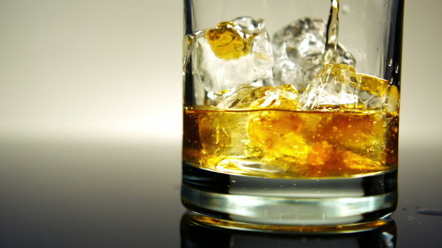 Pouring Whiskey on Ice in glass