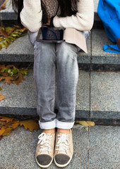 Happy hipster holding a tablet pc in city park in autumn