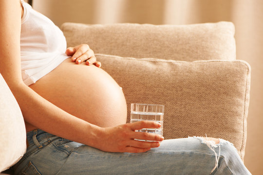 Pregnant Woman At Home Holding Glass Of Water