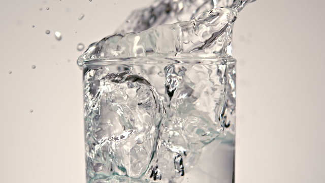 Ice cubes falling into glass of water