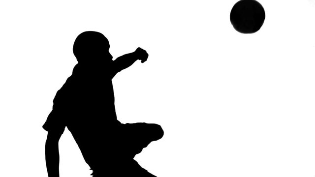 Silhouette of soccer player kicking ball
