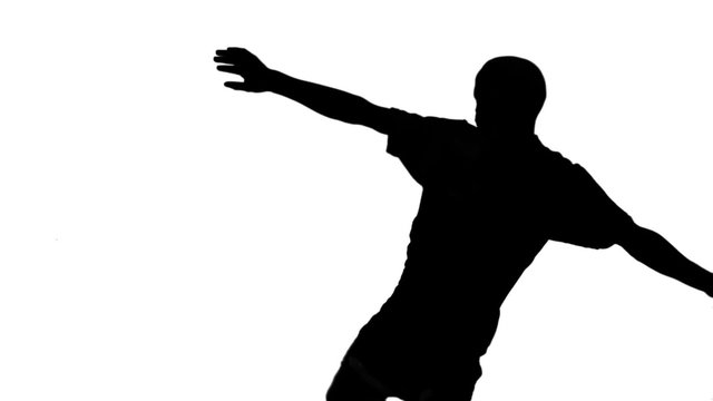 Silhouette of soccer player kicking ball 