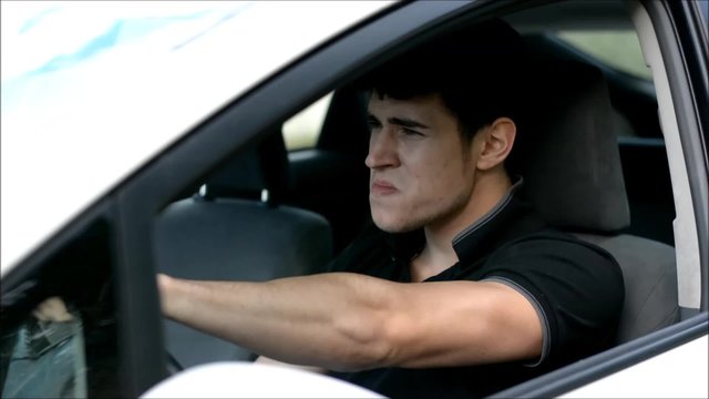 Young handsome man driving his car while drinking alcohol and honking in the traffic
