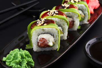 Premium quality sushi rolls with ginger wasabi and soy sauce over black background
