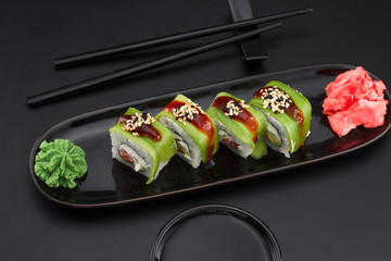 Premium quality sushi rolls with ginger wasabi and soy sauce over black background