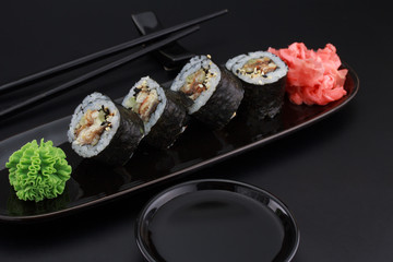 Premium quality sushi rolls with ginger wasabi and soy sauce over black background