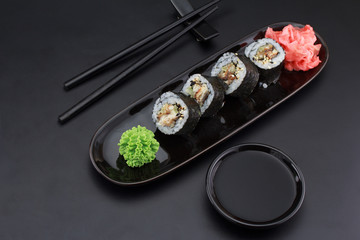 Premium quality sushi rolls with ginger wasabi and soy sauce over black background