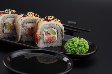 Premium quality sushi rolls with ginger wasabi and soy sauce over black background