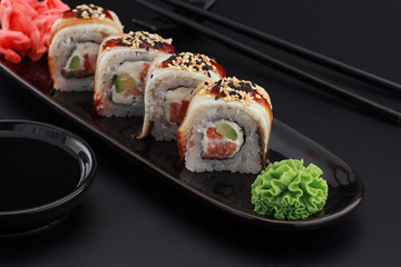 Premium quality sushi rolls with ginger wasabi and soy sauce over black background