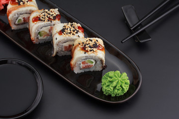 Premium quality sushi rolls with ginger wasabi and soy sauce over black background
