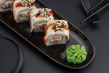 Premium quality sushi rolls with ginger wasabi and soy sauce over black background