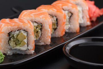 Premium quality sushi rolls with ginger and soy sauce over black background