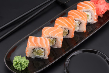 Premium quality sushi rolls with ginger wasabi and soy sauce over black background