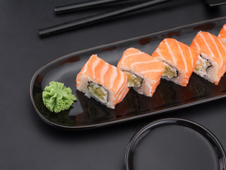 Premium quality sushi rolls with wasabi and soy sauce over black background