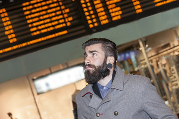 hipster businessman consult the board of timetable trains