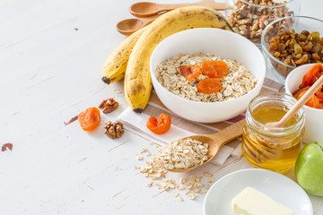 Granola ingredients on white wood background