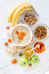 Granola ingredients on white wood background